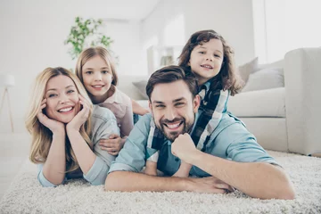 Fotobehang Photo of four members adopted family lying floor toothy smiling fluffy carpet cozy apartments © deagreez