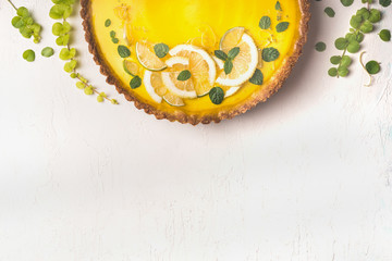 Food background with lemon tart topped with citrus slices and zest on white table background, top view. Copy space. Close up. Traditional french cuisine - obrazy, fototapety, plakaty