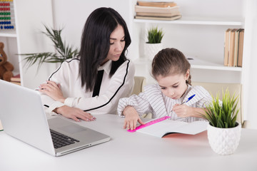 Mother and daughter sitting with computer together at the desk