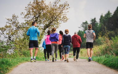 Rear view of group of multi generation people running a race competition in nature.