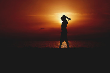 Silhouette of Young Man Practicing Yoga. Orange Sundown on the Seacoast.