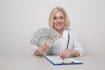 Female medicine worker in cabinet smiling and holding money isolated