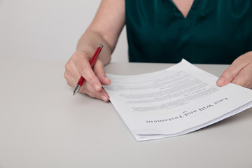 Closeup photo of woman's hands holding paper documents and a pen sitting on the desk