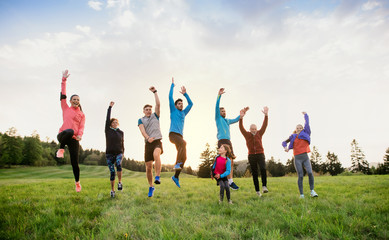 A large group of multi generation sport people standing in nature, jumping.