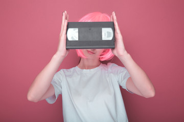 Young girl 90s and VHS cassette on pink background.