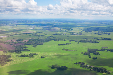 Obraz premium Green fields and forests, blue sky and white clouds background panoramic aerial view, sunny summer day europe nature landscape top view, beautiful grassland meadows and trees panorama look from above