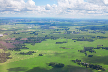 Green fields and forests, blue sky and white clouds background panoramic  aerial view, sunny summer day europe nature landscape top view, beautiful grassland meadows and trees panorama look from above