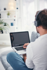 Man listening to music and using laptop in the living room.
