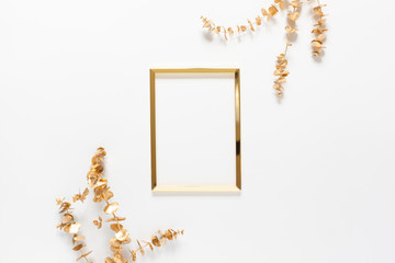 Obraz premium Autumn composition. Golden frame with a gold spray painted natural eucalyptus branches on white background. Flat lay, top view, copy space.