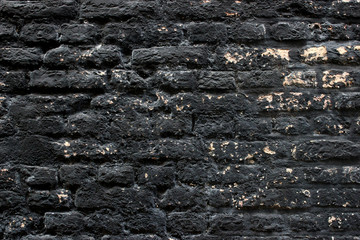 Weathered black painted brickwork wall background texture with some yellow spots