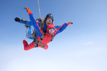 Fototapeta na wymiar Skydiving. Tandem jump. A strong man and a young woman are falling in the sky.