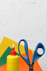 Scissors, glue and colored paper for application. They are located vertically. Against the...