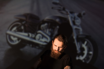 Obraz na płótnie Canvas brutal male biker looking through the slides of his motorcycle.