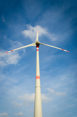Un'elica di un parco eolico vista dal basso si staglia contro il cielo e le nuvole