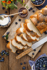 Challah bread  sprinkled with poppy seeds,  Challah bread slices on a wooden table, top view, ...