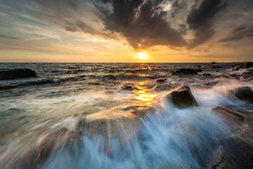 White waves crashing on the rocks at sunset