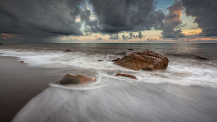 White waves crashing on the rocks at sunset