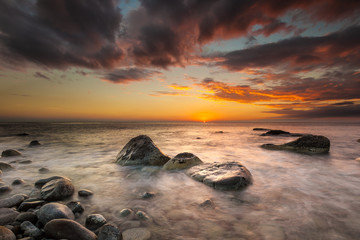 White waves crashing on the rocks at sunset