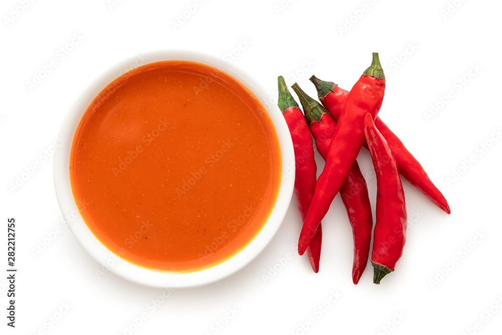 Wall mural peri peri chilli sauce in a white ceramic bowl next to a pile of red chillies isolated on white from