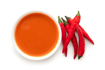 Poster Pantone 2022 very peri Peri peri chilli sauce in a white ceramic bowl next to a pile of red chillies isolated on white from above.  © Moving Moment