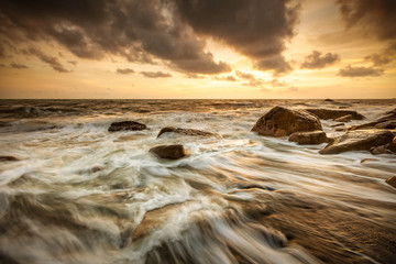 White waves crashing on the rocks at sunset