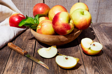Fresh red apples with green leaves on a wooden old table. On a wooden background with sliced apple. Free space for text. soft focus