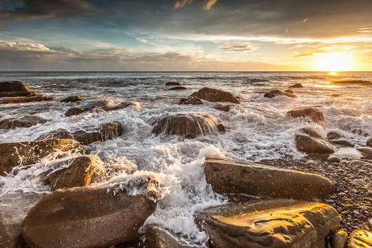 White waves crashing on the rocks at sunset