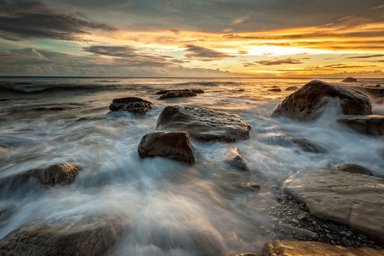 White waves crashing on the rocks at sunset