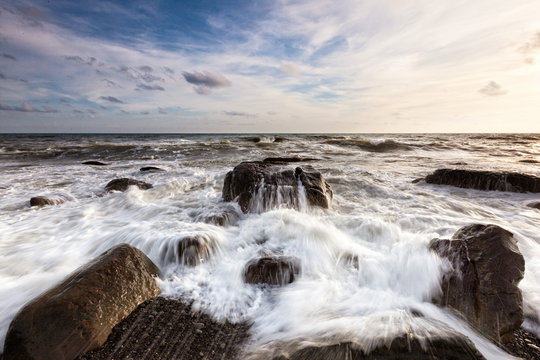 White waves crashing on the rocks at sunset