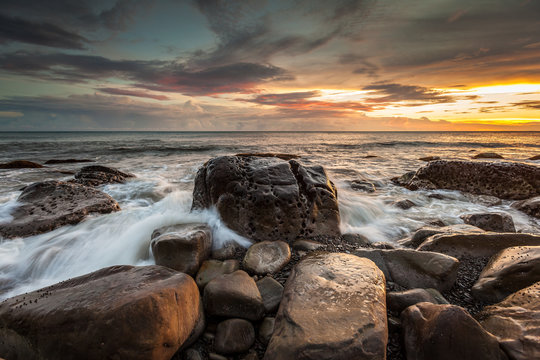 White waves crashing on the rocks at sunset