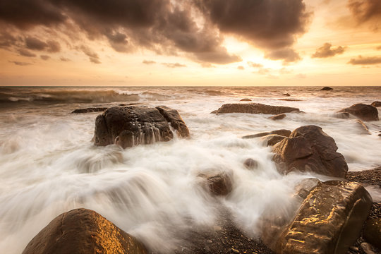 White waves crashing on the rocks at sunset