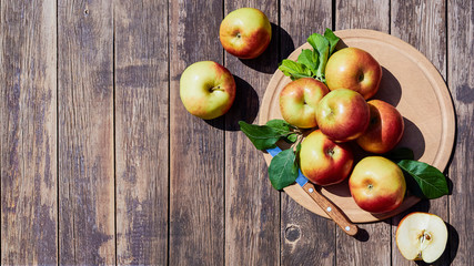 Fresh red apples with green leaves on a wooden old table. On a wooden background. Free space for text. view from above