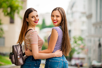 Back side photo of charming youth hugging with tooth smile wearing striped t-shirt denim jeans in city outdoors