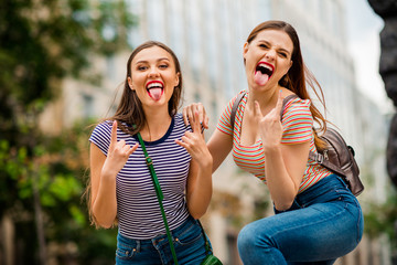 Portrait of cool youth with red brunette hair pomade fooling showing rocker symbol wearing striped t-shirt denim jeans bag backpack handbag in town