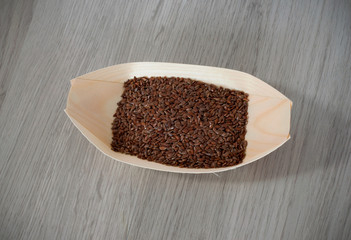 Flax seeds in a eco, wooden container isolated on wooden background