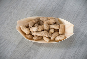 Peanuts in a eco, wooden container isolated on wooden background