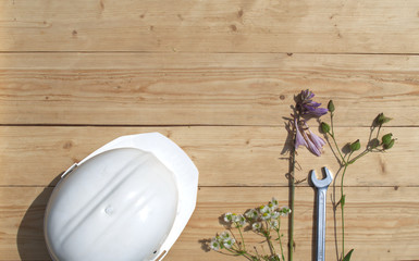 On a wooden table are a white construction helmet with wrenches.