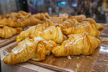 Puffy croissants with cream cheese sauce on top at bakeshop