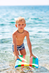 Happy little boy playing in the waves at the seaside