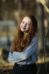 Portrait of a cute girl with long red hair outdoors.