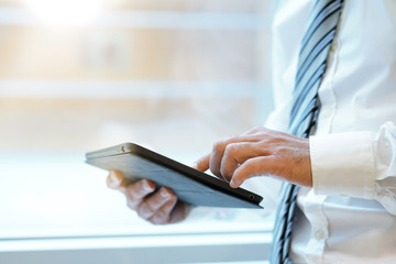 Close up of businessman's hands using tablet in contemporary office