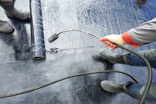 Professional installation of waterproofing on the concrete foundation Two worker at construction site.