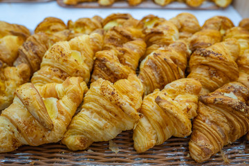 Pile of puffy cheese croissants for sale at patisserie 