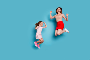 Fototapeta na wymiar Full size photo of foxy little lady and her excited mom jumping high wear casual clothes isolated blue background