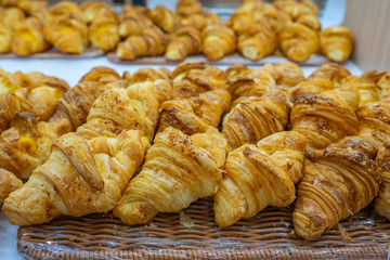 Pile of puffy croissants on shelf for sale at patisserie