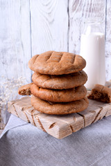 Stack of round brown rye flatbread against the white wooden background. Bottle of milk in the background