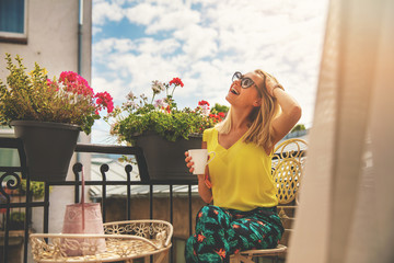 attractive young woman enjoying vacations and drinking coffee on hotel balcony