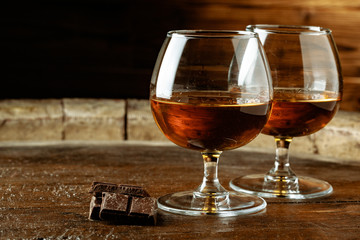 Two glasses of bourbon or scotch, or brandy and pieces of dark chocolate