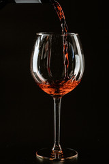 Red wine being poured in a wine glass on a dark background