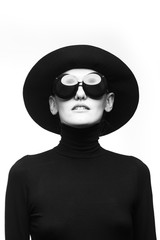 Stylish black and white portrait of elegant slim girl in glasses and a hat.